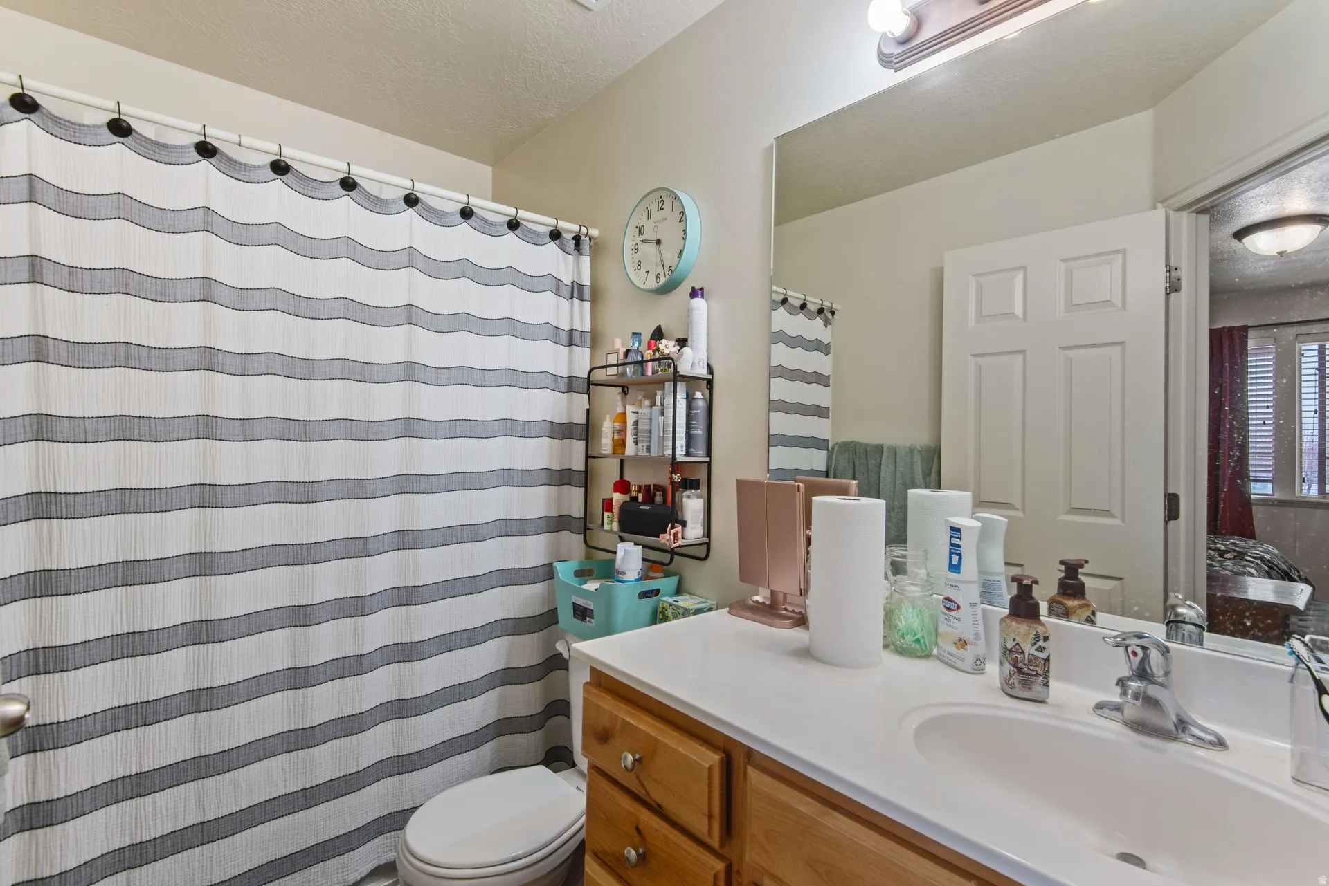 Bathroom featuring vanity, a shower with shower curtain, ensuite bathroom, and a textured ceiling