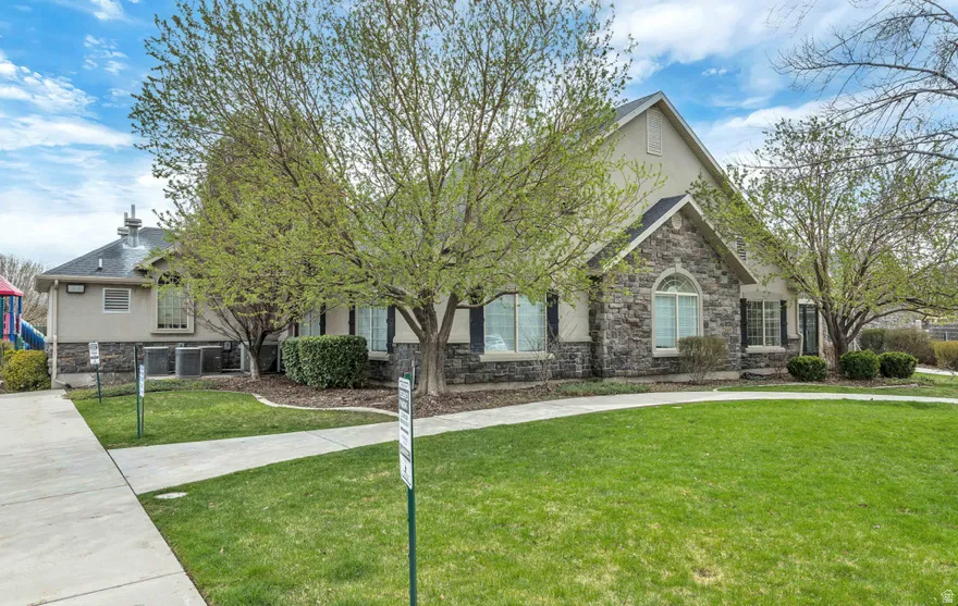 View of front of home featuring stone siding, a front lawn, roof with shingles, and stucco siding