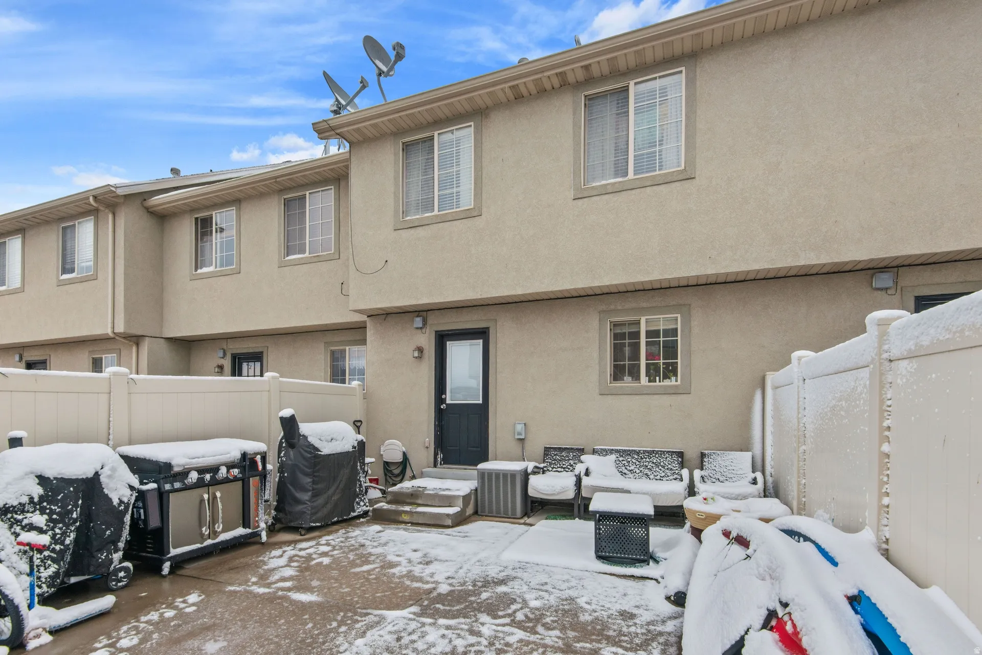 Snow covered house with a patio, stucco siding, and outdoor lounge area