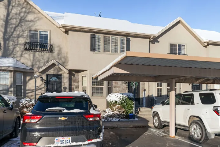 View of front of home with stucco siding, stone siding, and covered parking