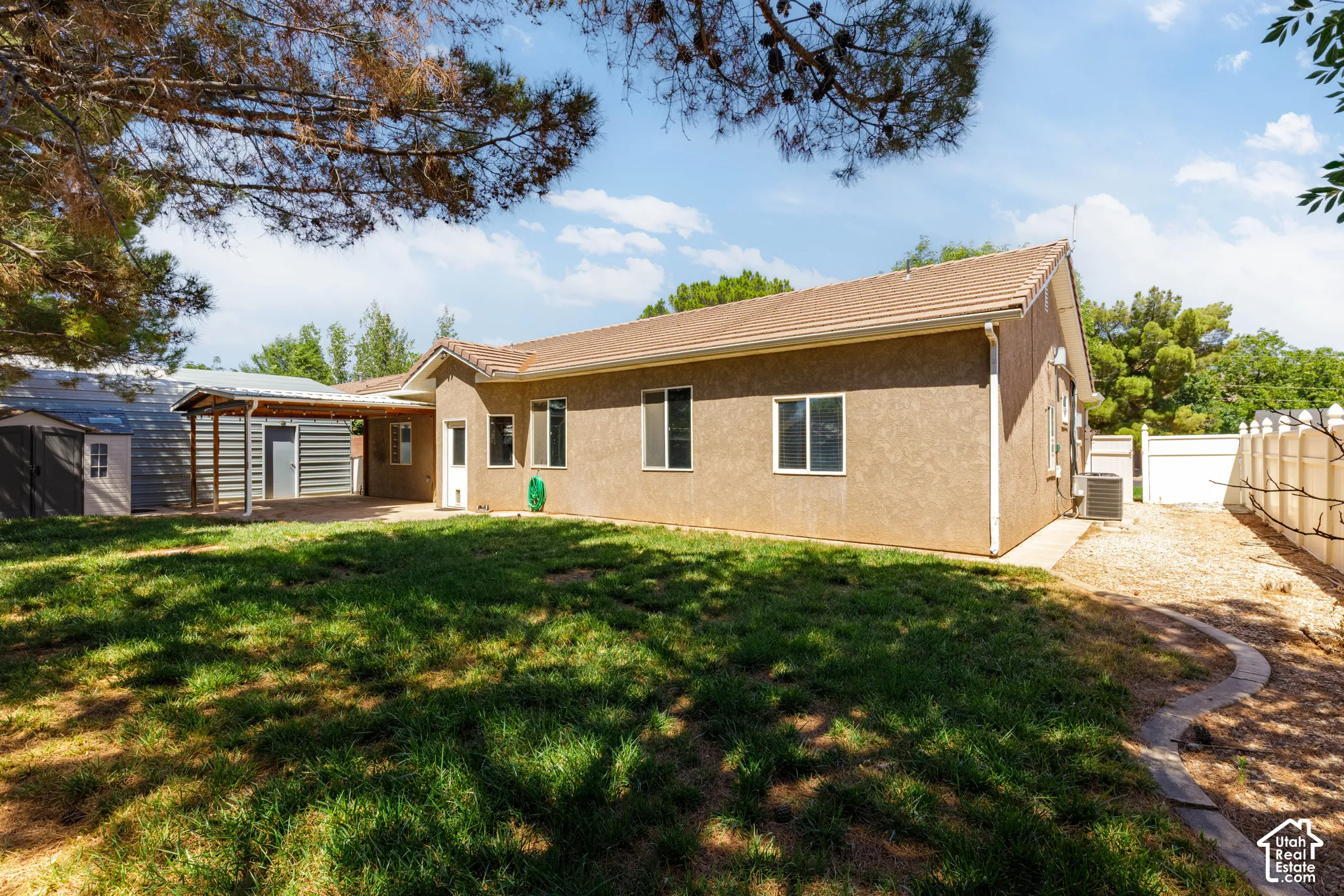 Expansive rear yard featuring a grass lawn, gravel side yard, and a covered patio area
