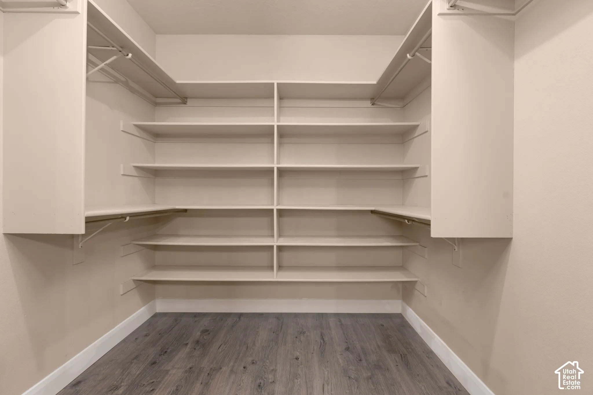 Primary walk in closet with wood finished floors