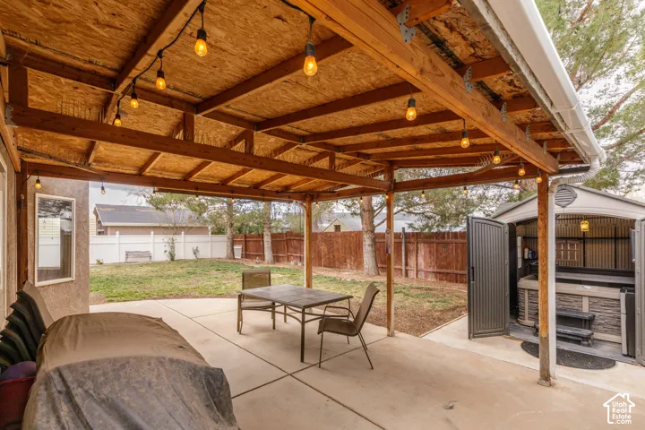 Fenced backyard with a patio, an outdoor structure, and outdoor dining area and enclosed hot tub