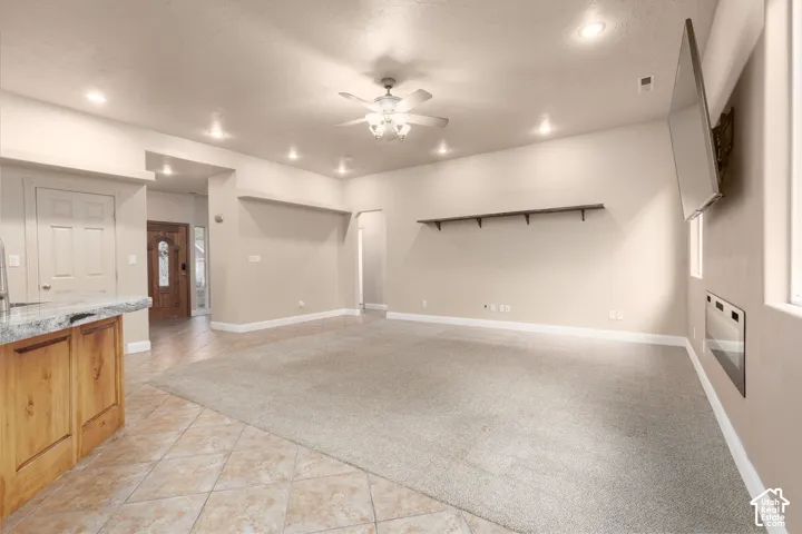 Living room with ceiling fan, light tile patterned floors, and recessed lighting