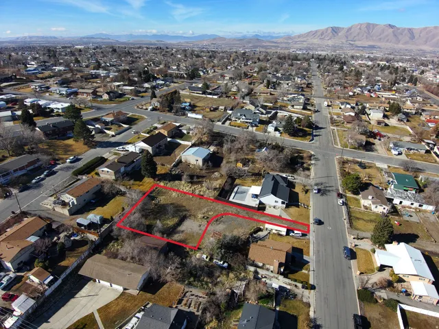 Aerial perspective of suburban area with property parcel outlined and a mountainous background