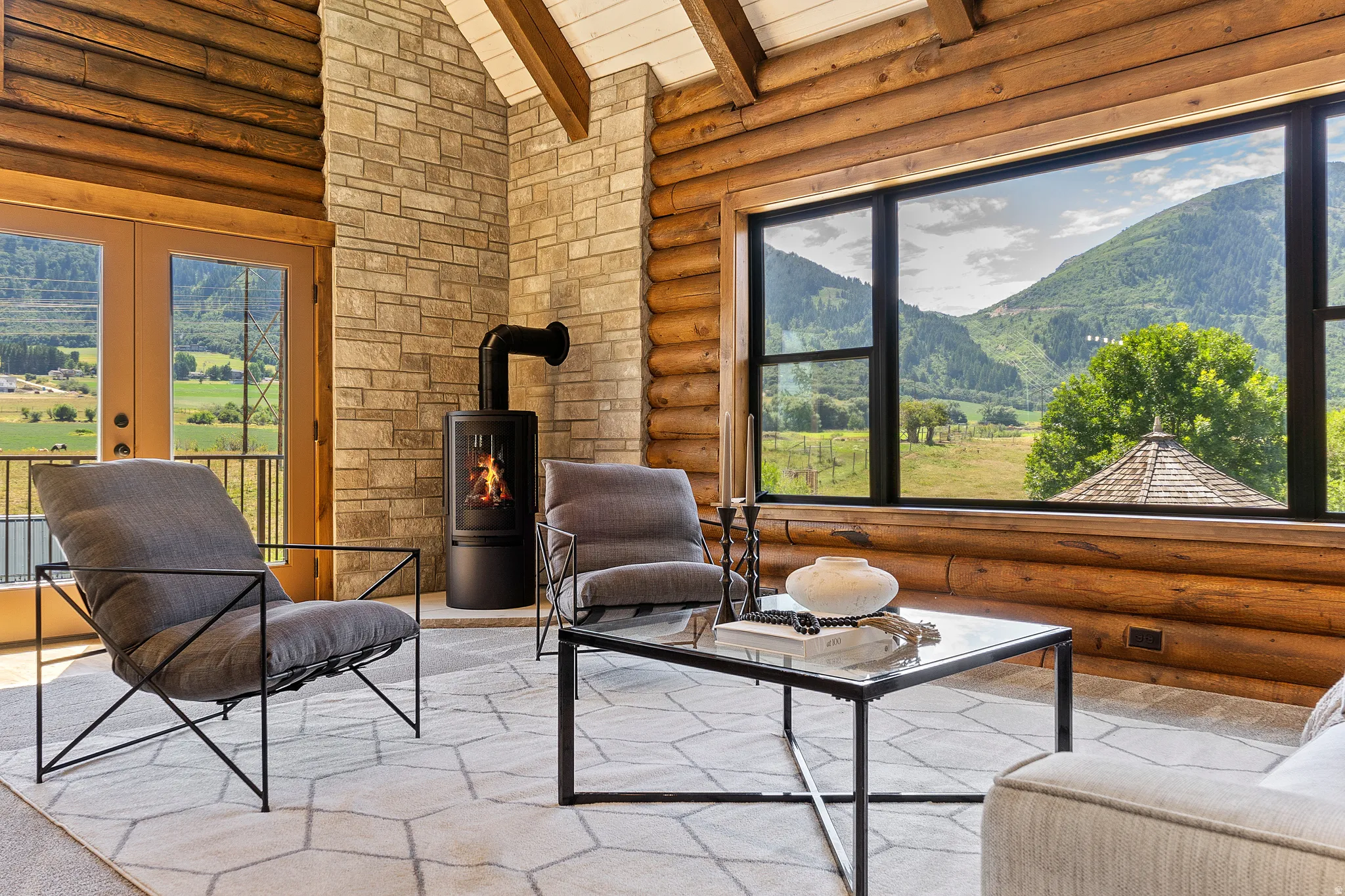 Living area featuring rustic walls, a mountain view, a high wood beamed ceiling, french doors, and a wood stove