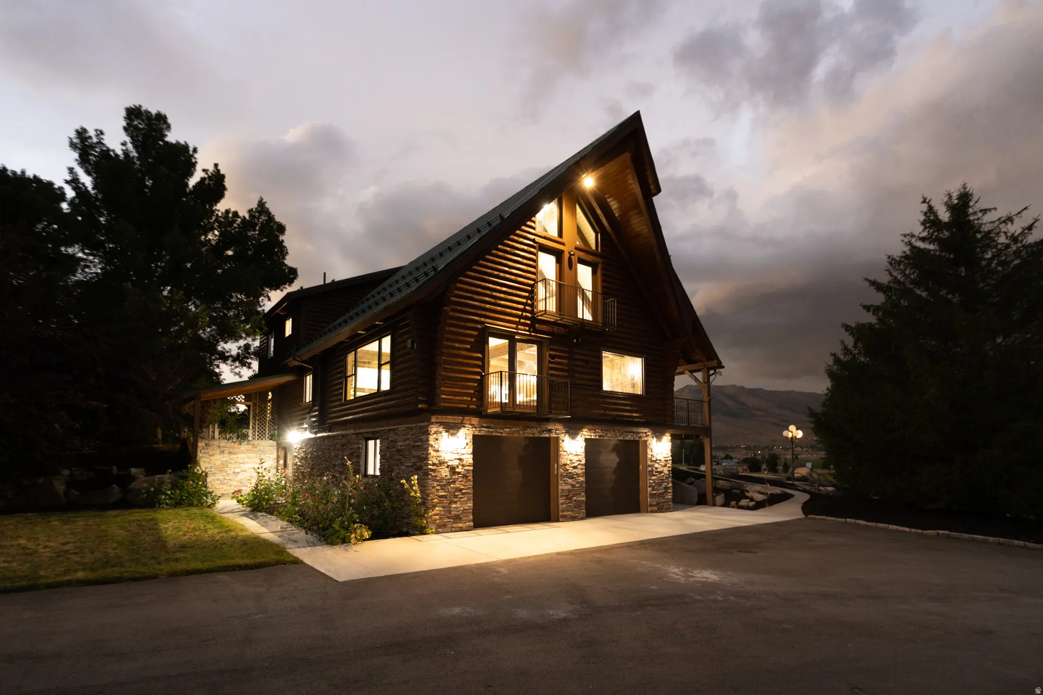 View of side of property featuring stone siding, an attached garage, driveway, and log siding