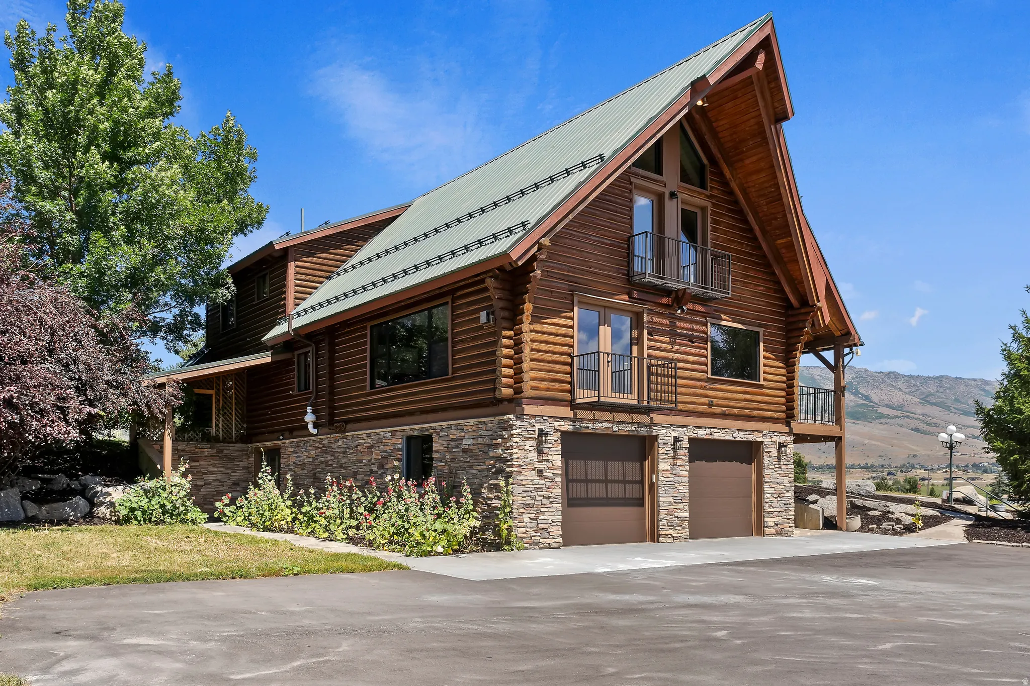 View of property exterior featuring log exterior, stone siding, a garage, and a mountain view
