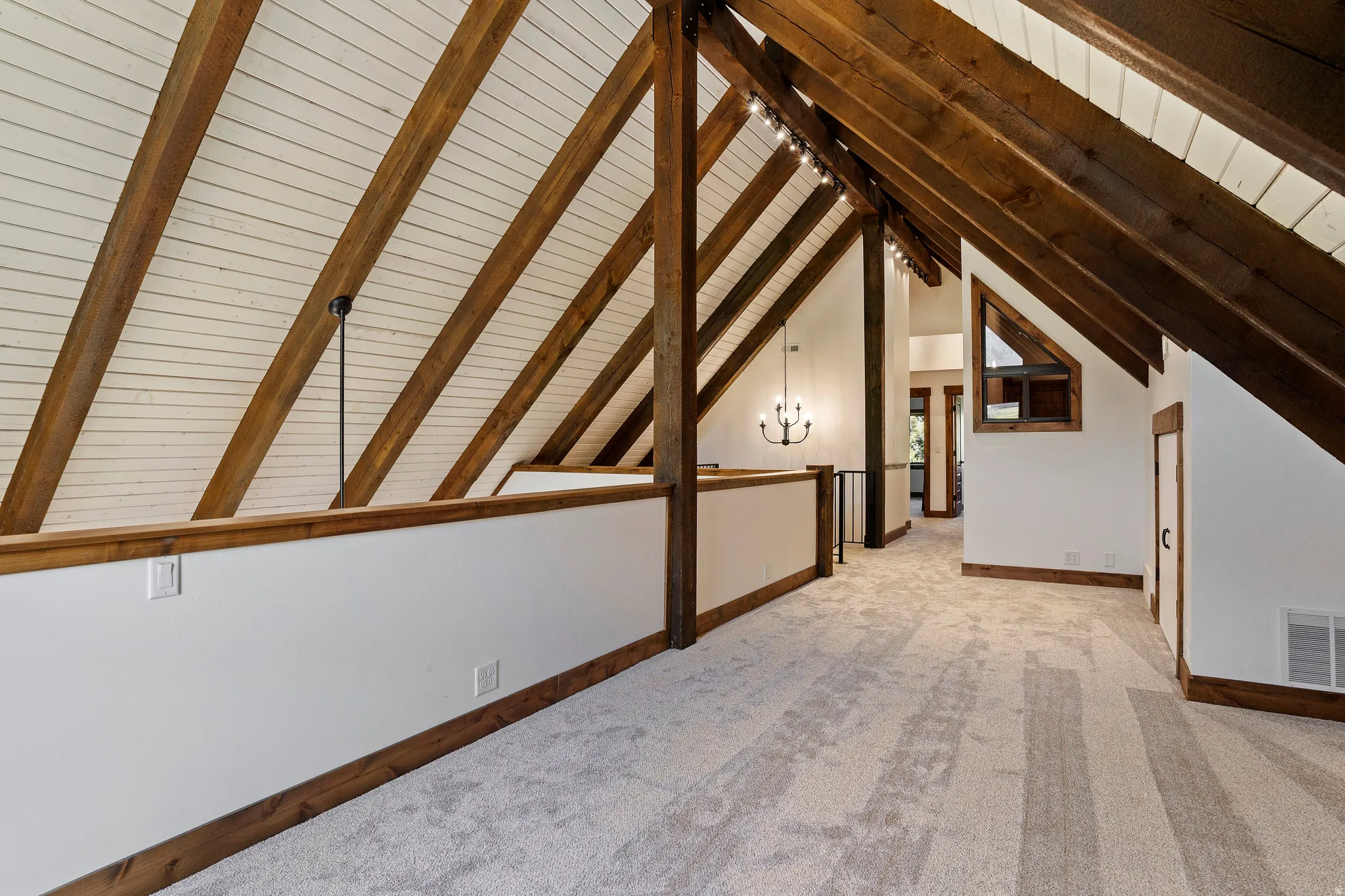 Additional living space featuring light carpet, suspended lighting, and a wood ceiling with exposed beams