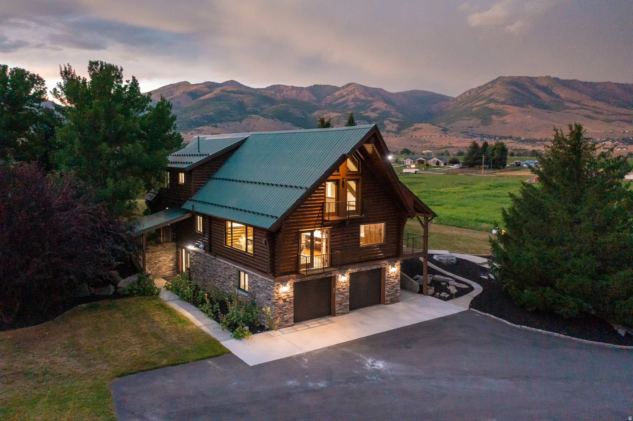 View of front facade featuring stone siding, a front lawn, a garage, and log exterior