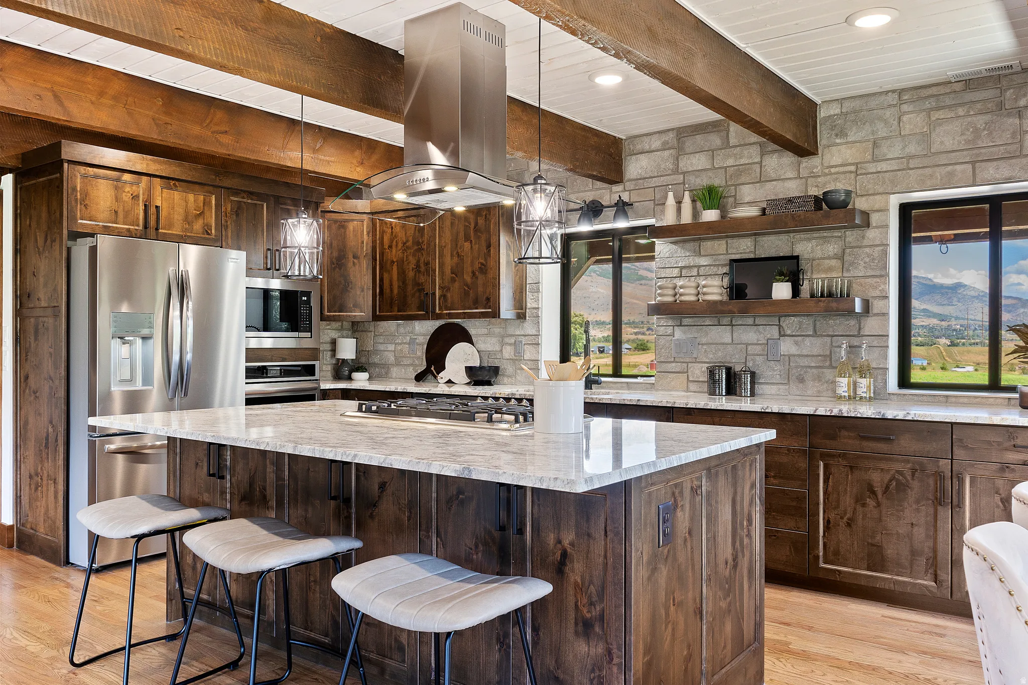 Kitchen with stainless steel appliances, hanging light fixtures, dark wood finish cabinetry, beam ceiling, and a center island