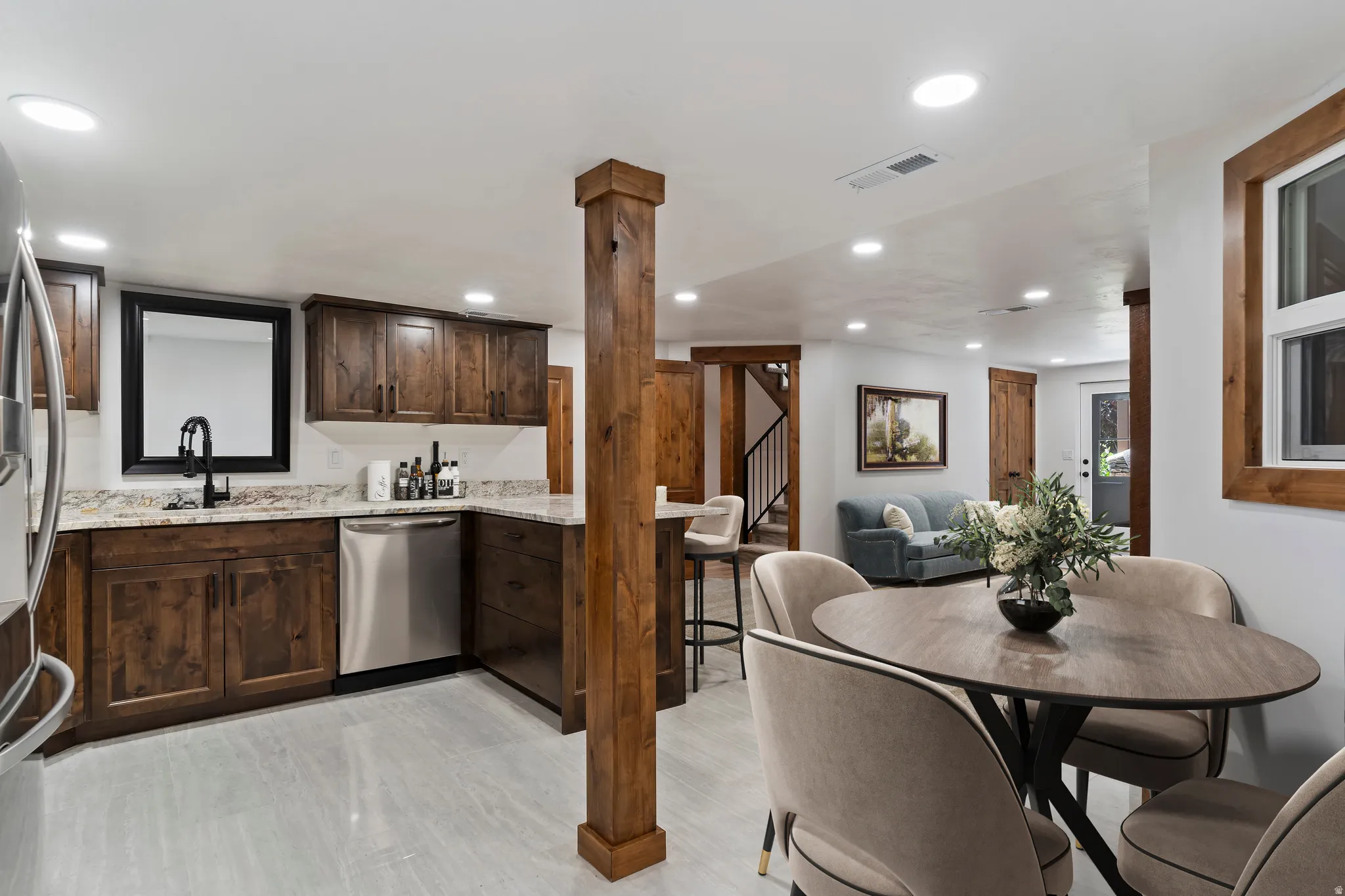 Kitchen with dark wood finish cabinetry, stainless steel appliances, light stone countertops, recessed lighting, and open floor plan