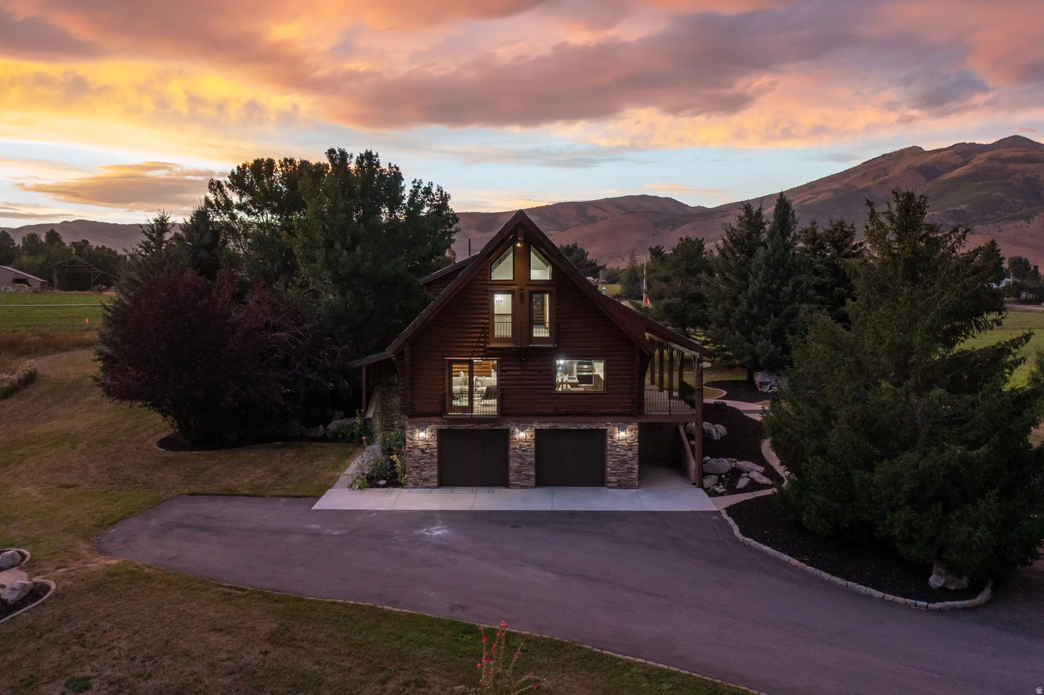 View of front facade with stone siding, a mountain view, an attached garage, driveway, and a lawn