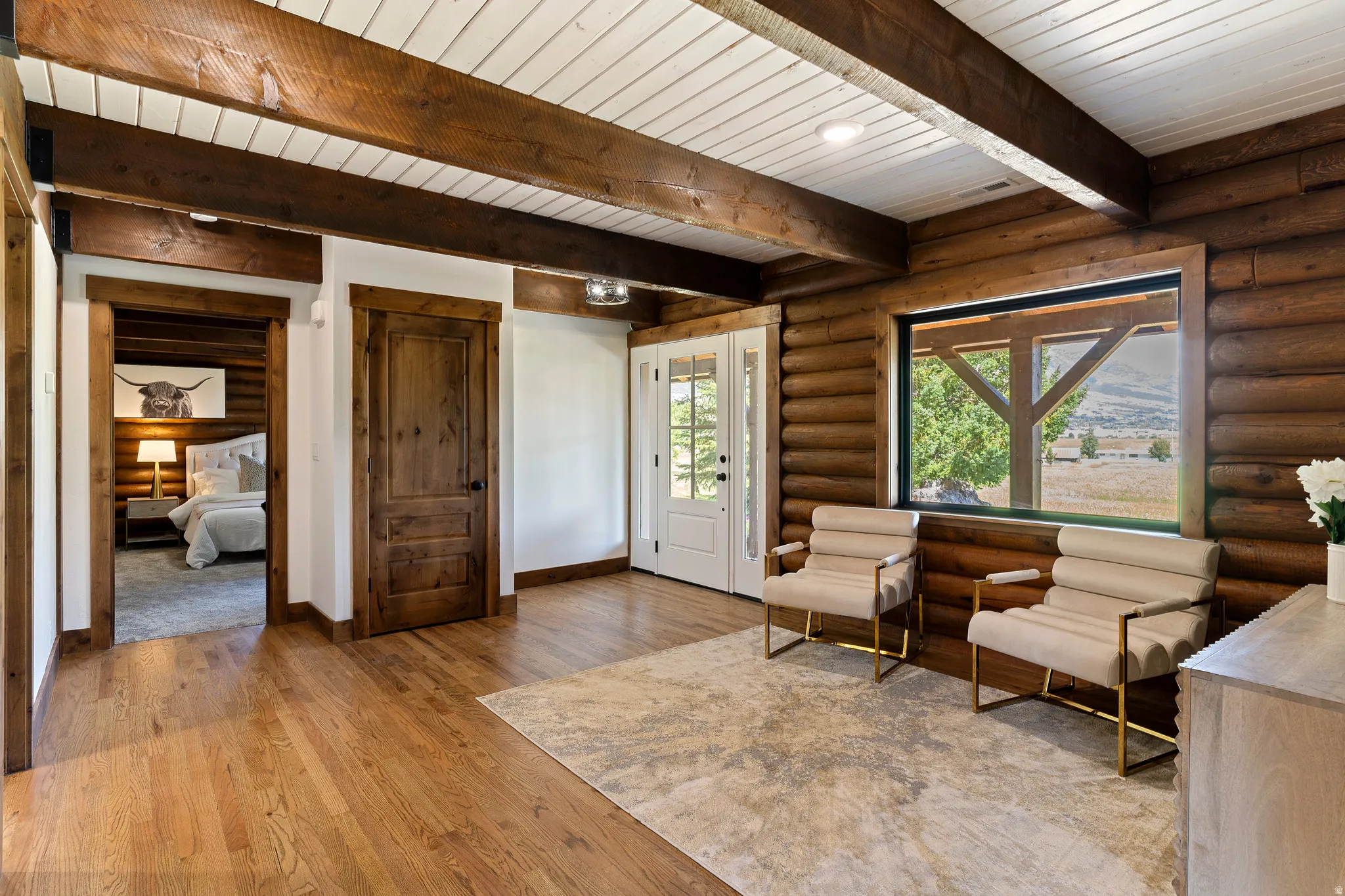Living area with rustic walls, wood-type flooring, and beamed ceiling
