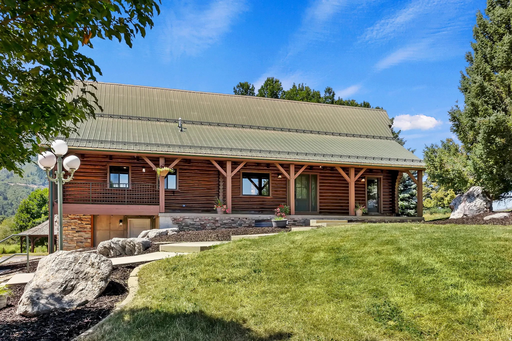 Back of house featuring a metal roof, a yard, a porch, and stone siding