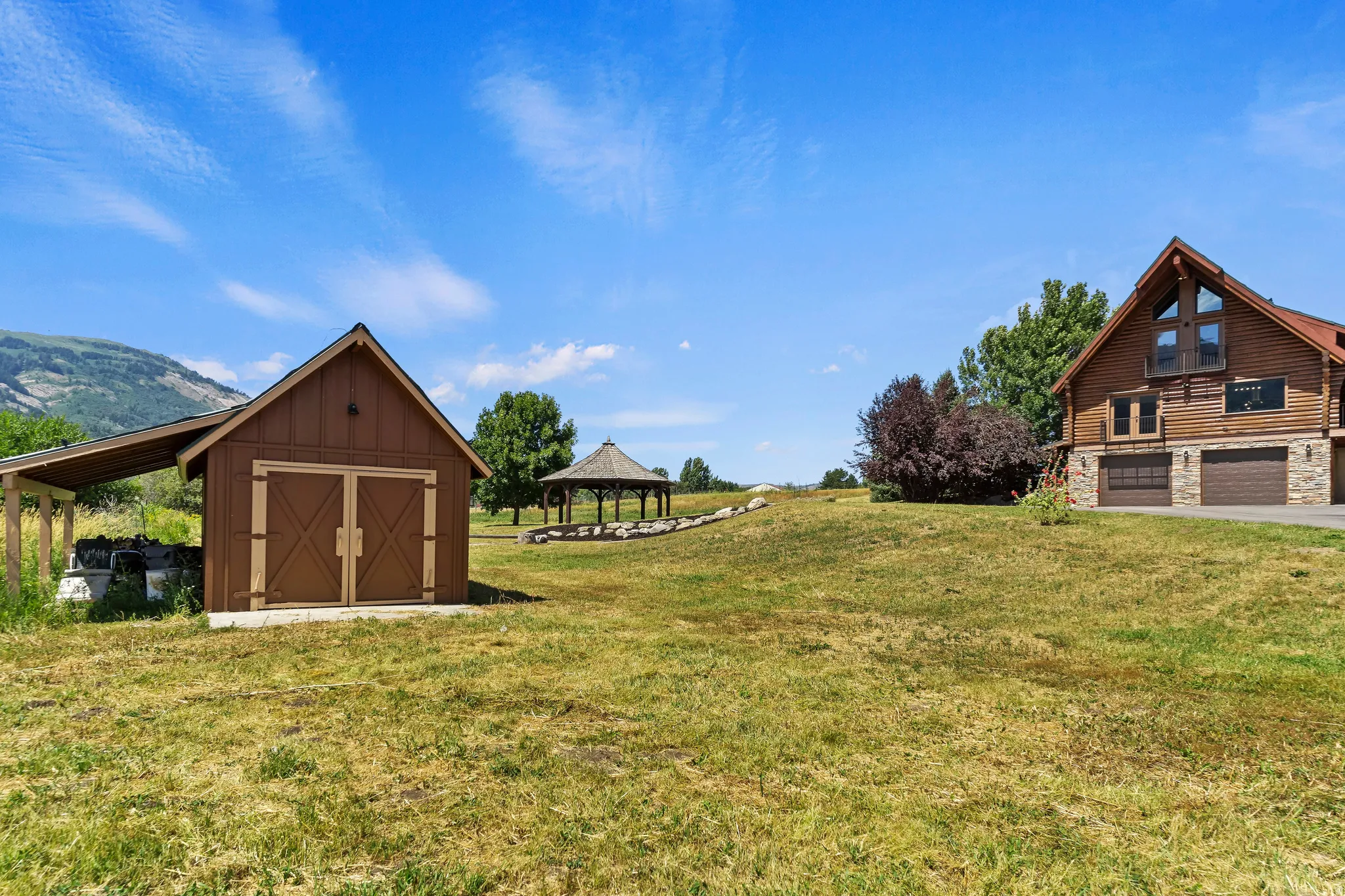 View of grassy yard featuring a gazebo, a storage unit, and a mountain view