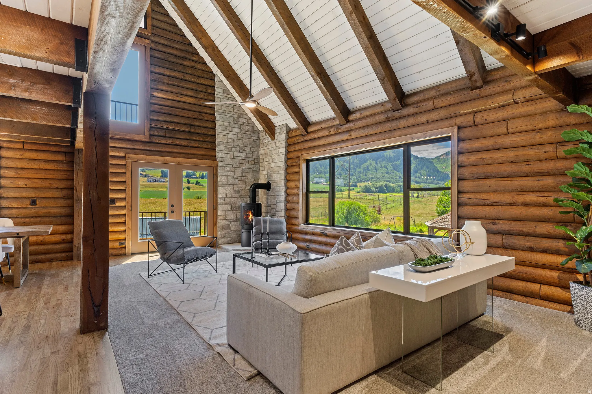 Living room featuring rustic walls, a wood stove, a high wood beamed ceiling, french doors, and wood finished floors
