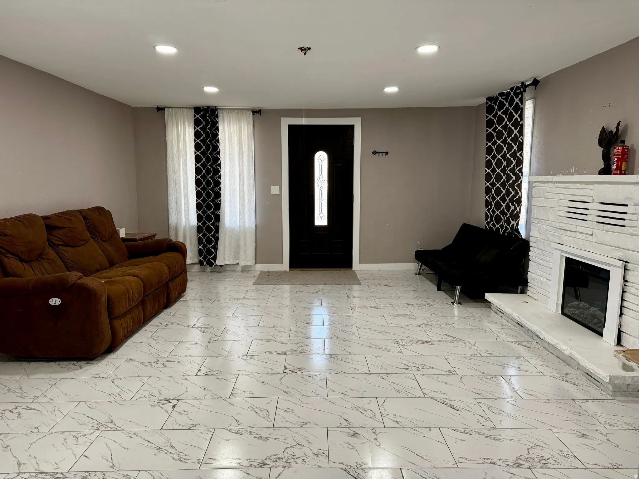 Living room featuring recessed lighting, a fireplace, and light marble finish floors