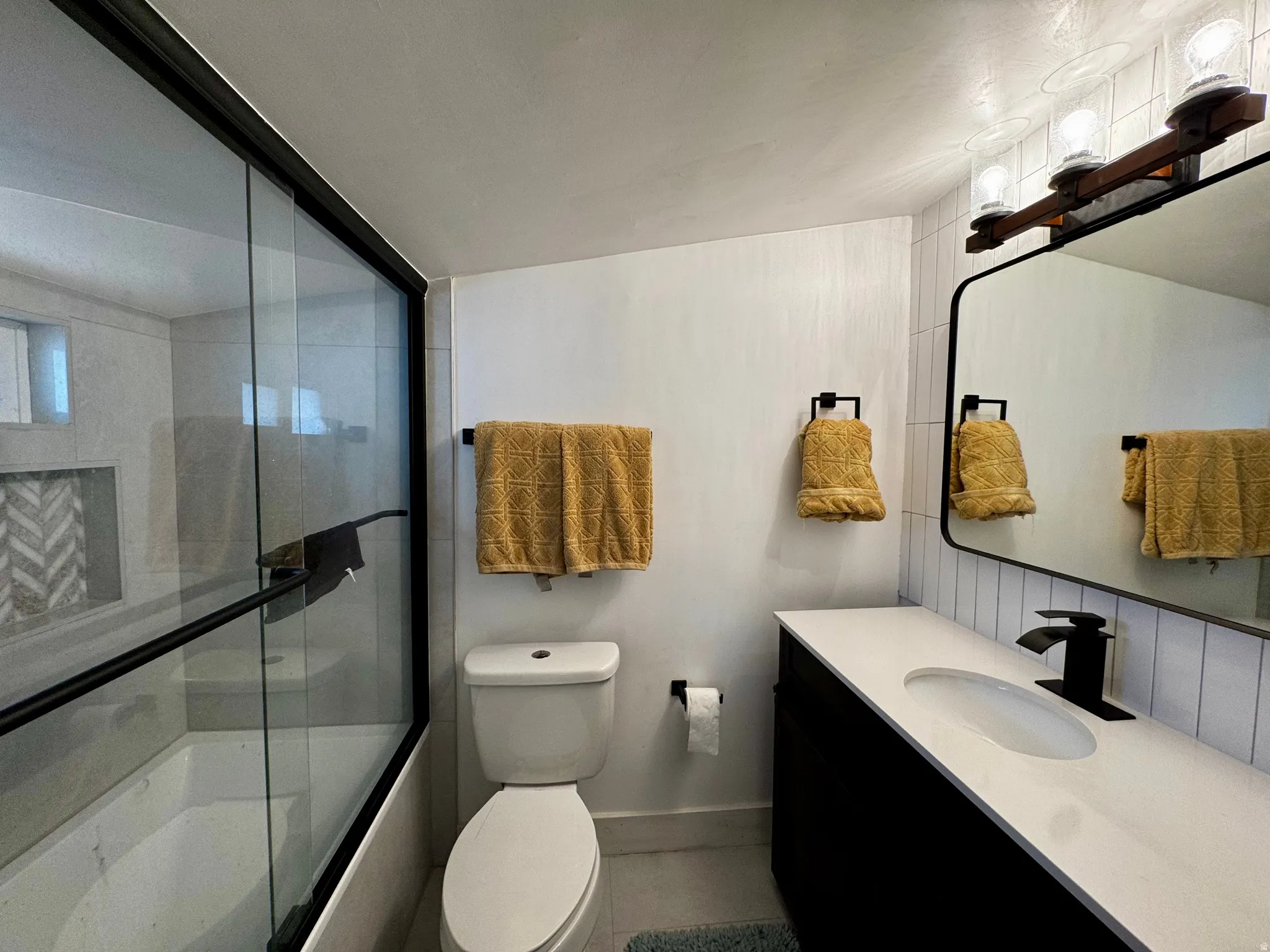 Bathroom featuring bath / shower combo with glass door and vanity