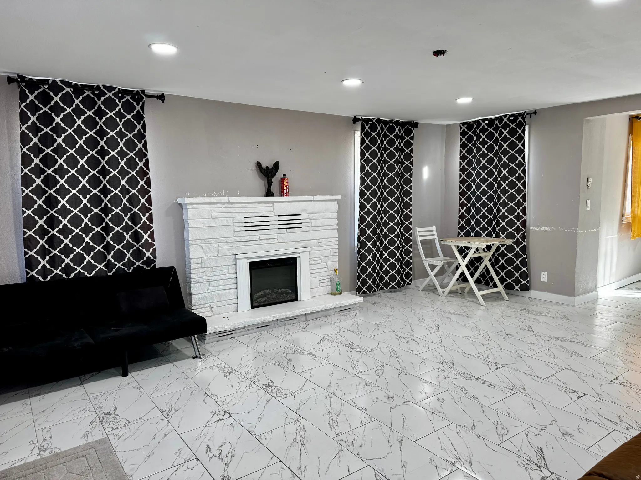 Living room with light marble finish flooring, recessed lighting, and a fireplace