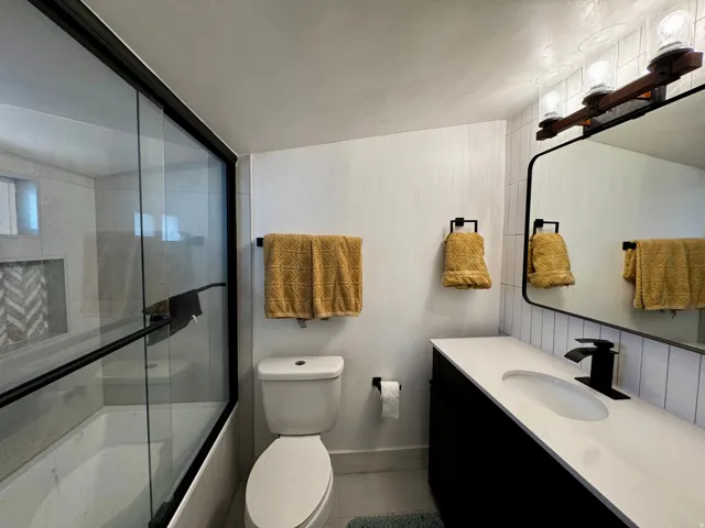 Bathroom featuring bath / shower combo with glass door and vanity