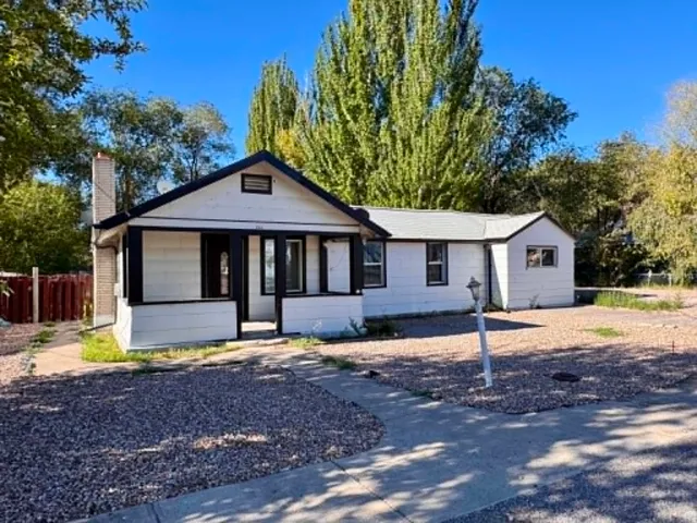 Charming single-story residence featuring a modern black and white exterior with a covered front porch entry