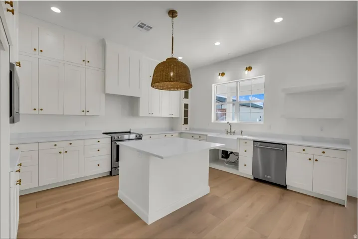 Kitchen with white cabinetry, stainless steel appliances, light wood finished floors, open shelves, and a kitchen island