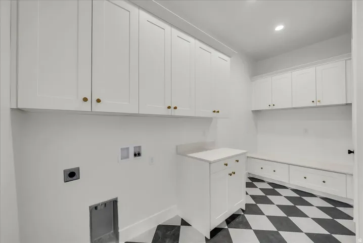 Laundry room with dark floors, hookup for a washing machine, electric dryer hookup, recessed lighting, and cabinet space