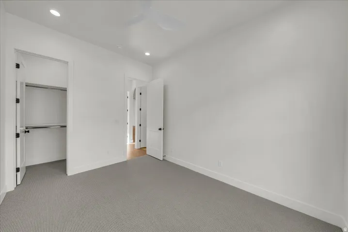 Unfurnished bedroom with carpet, ceiling fan, recessed lighting, and a spacious closet