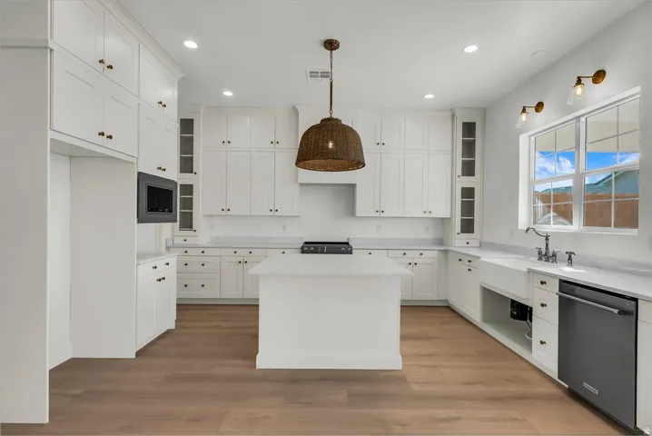 Kitchen with glass fronted cabinets, a center island, stainless steel appliances, and decorative light fixtures