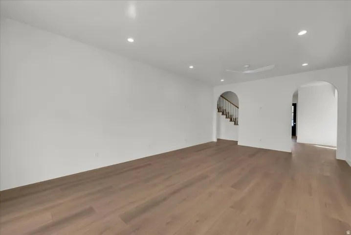 Spare room with arched walkways, wood finished floors, and recessed lighting