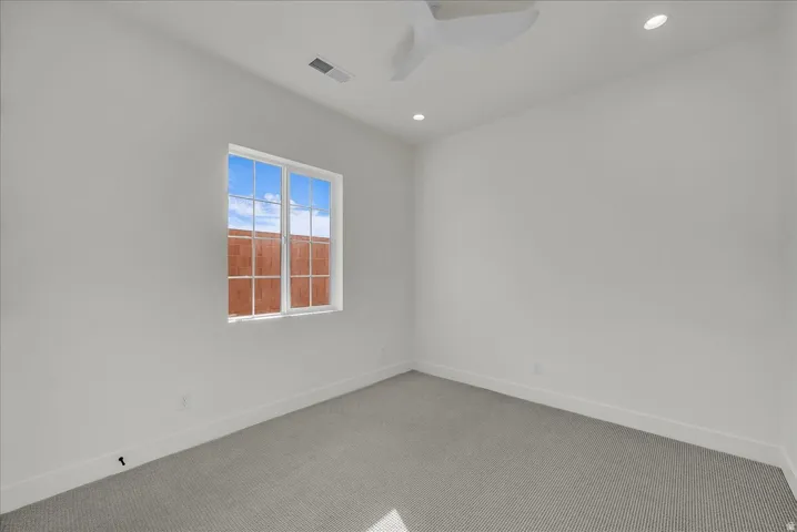 Carpeted spare room with a ceiling fan and recessed lighting