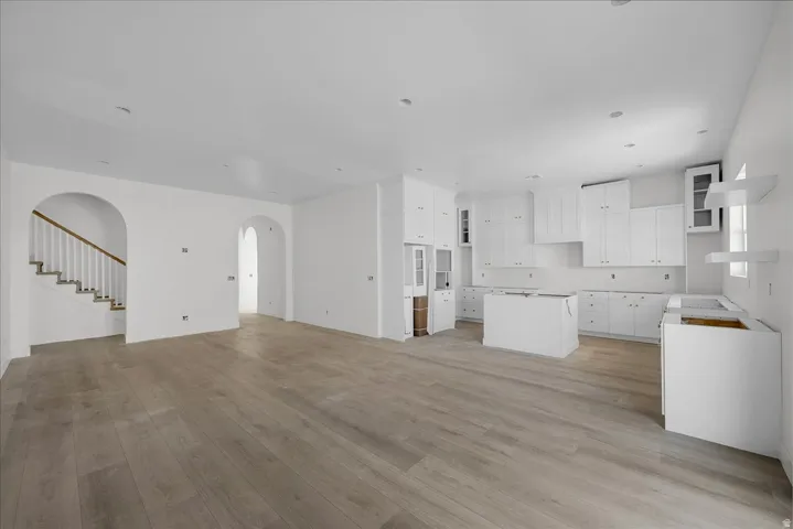 Unfurnished living room with arched walkways and light wood-style floors