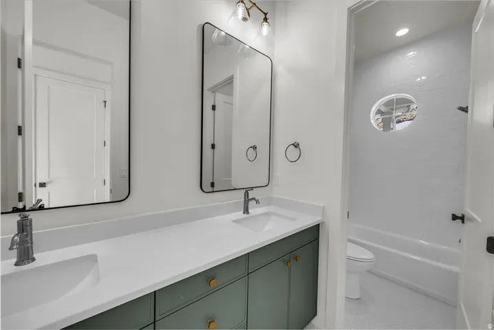 Bathroom with double vanity, shower / bathtub combination, recessed lighting, and light tile patterned floors