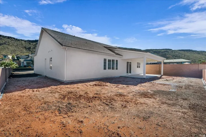 Back of house with a mountain view, a fenced backyard, and a patio