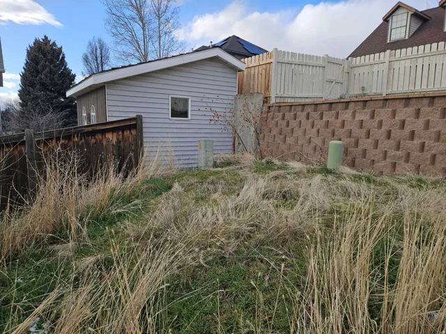 Detached outbuilding with light gray siding and white trim