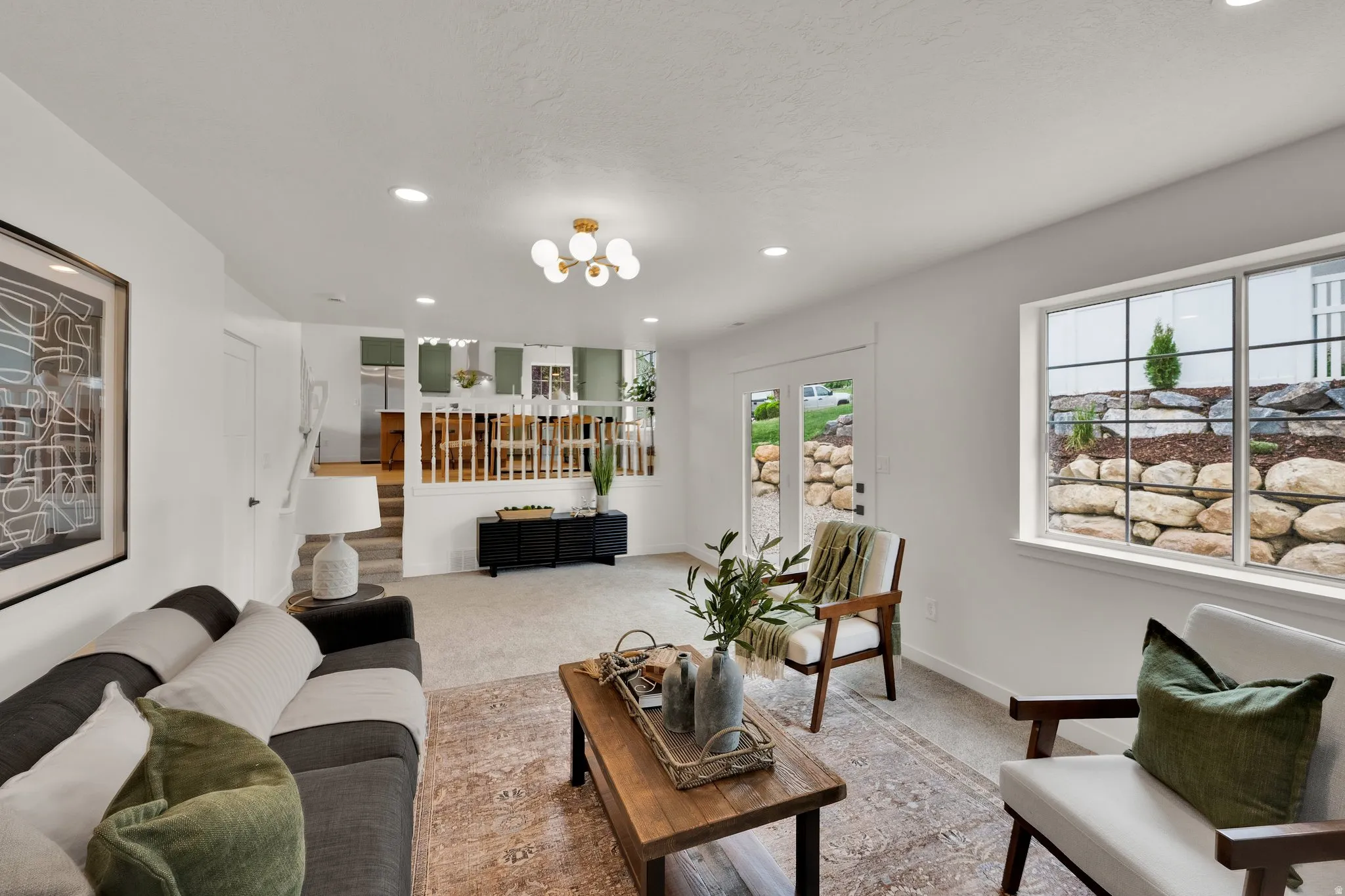 Carpeted living area featuring baseboards and hanging lights