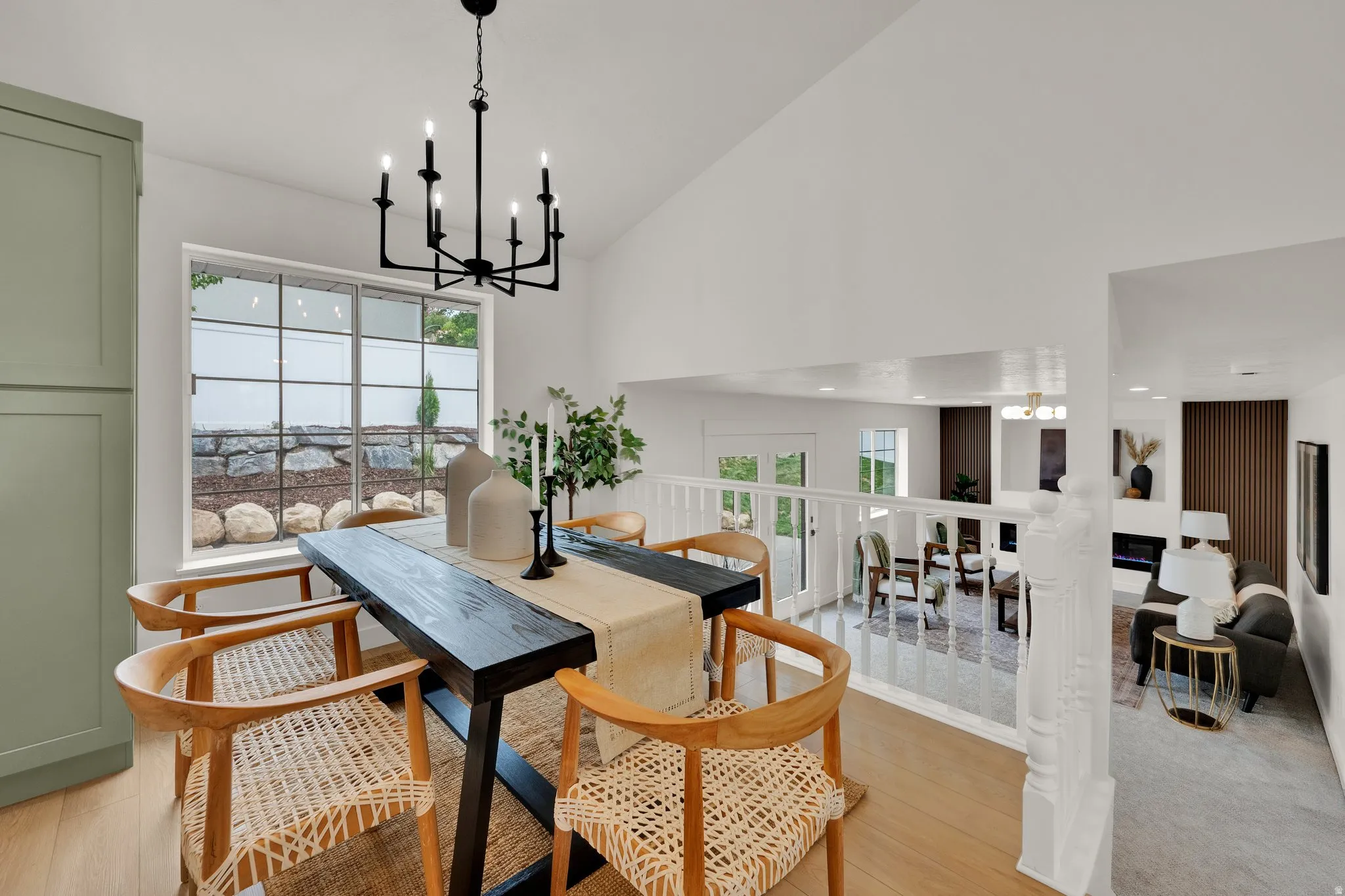 Dining room with suspended lighting, lofted ceiling, healthy amount of natural light, and light wood-style flooring