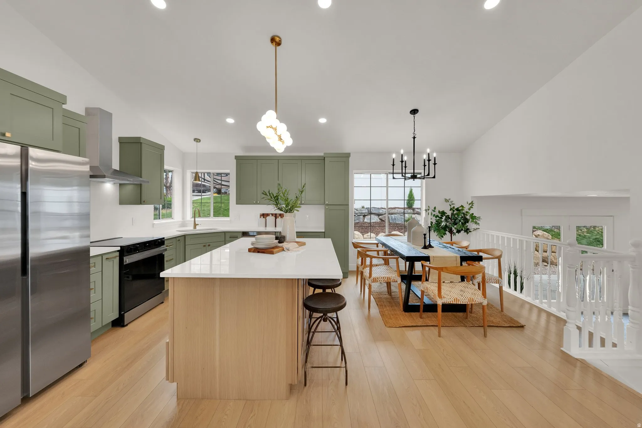 Kitchen featuring green cabinets, vaulted ceiling, freestanding refrigerator, range with electric stovetop, and a kitchen island