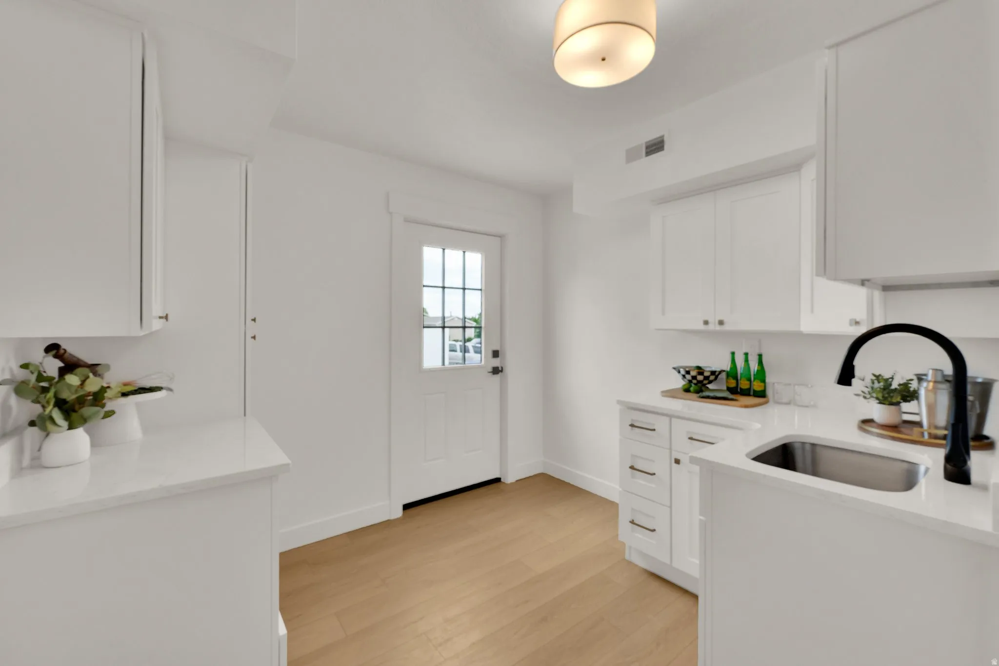 Kitchenette featuring light stone counters, white cabinets, and light wood-style floors