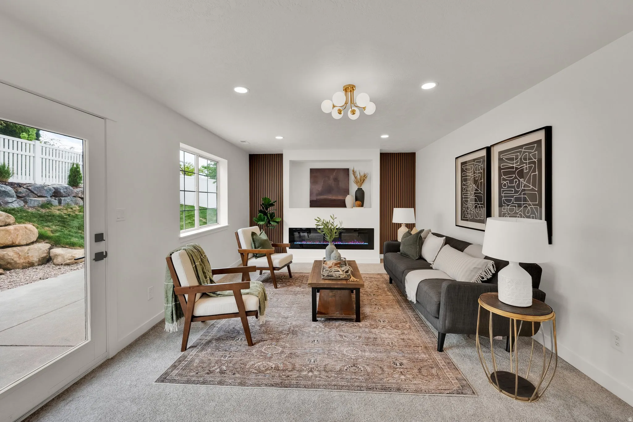 Living room featuring a glass covered fireplace, carpet, and suspended lighting