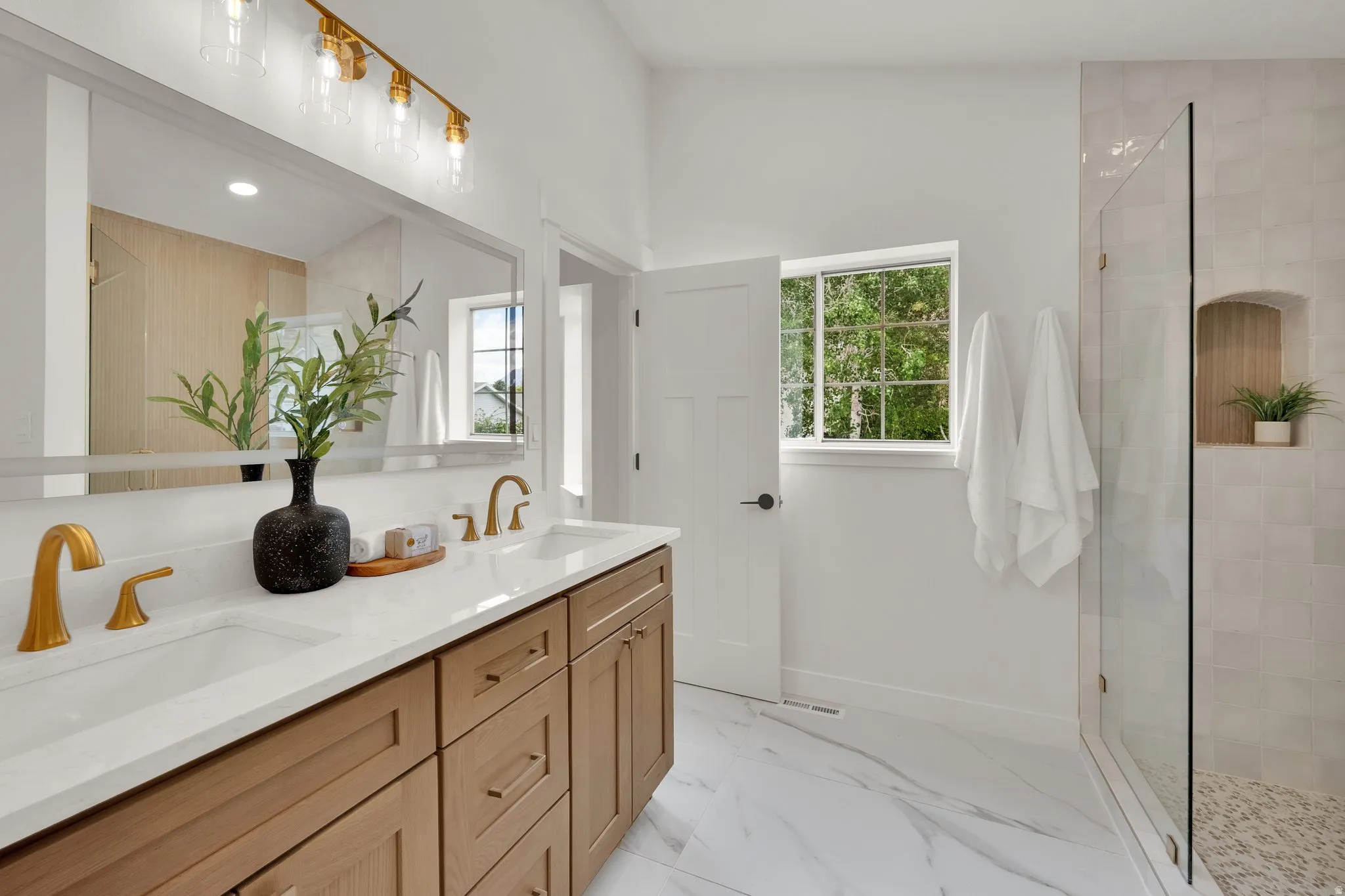 Full bathroom with double vanity, a walk in shower, light marble finish floors, and recessed lighting