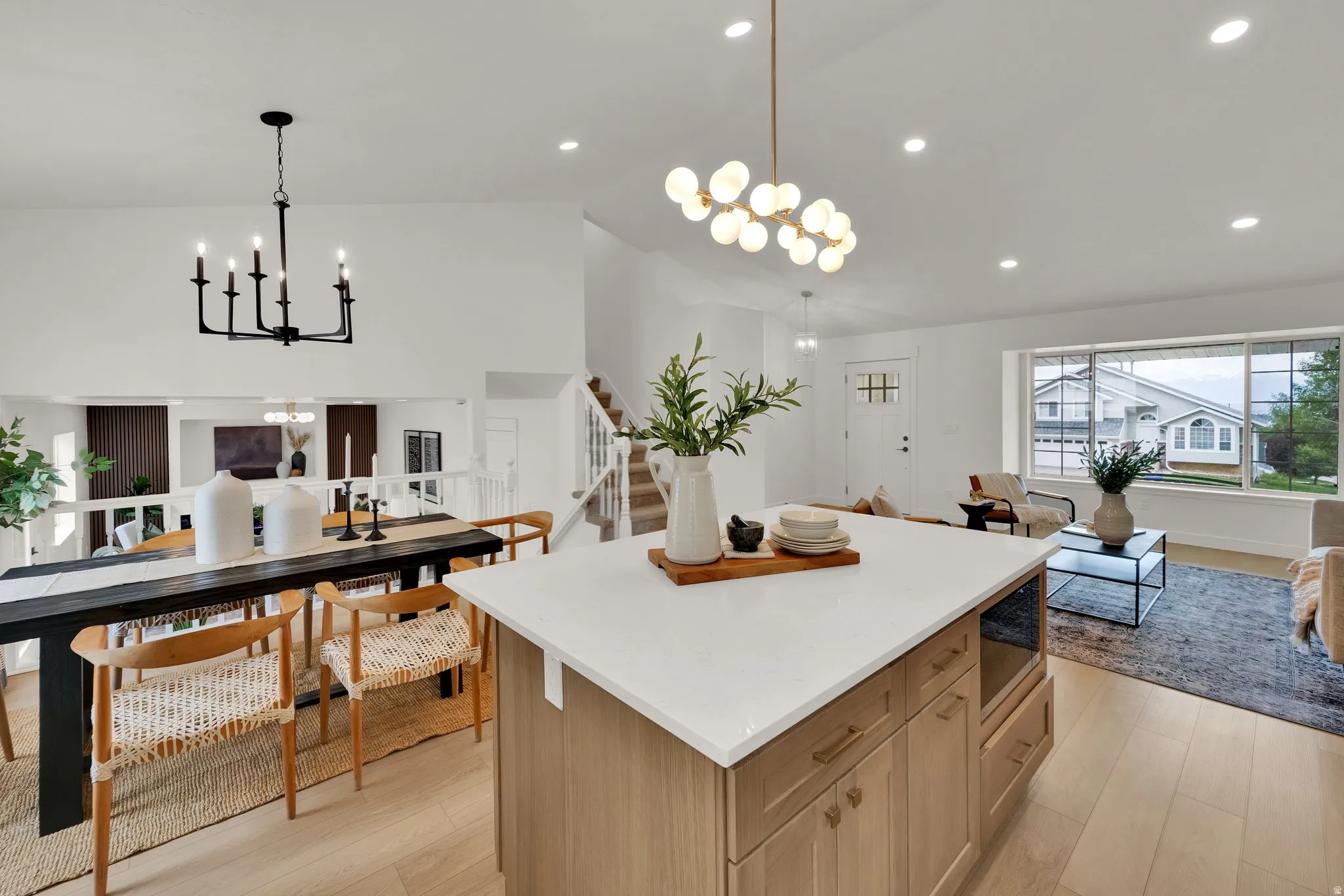 Kitchen featuring suspended lighting, open floor plan, a kitchen island, light stone countertops, and stainless steel microwave