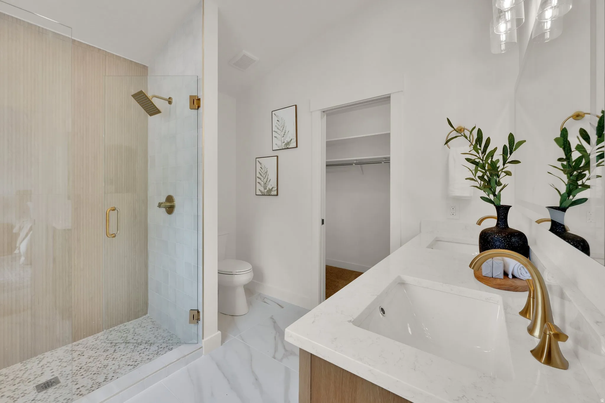 Primary Bathroom with a stall shower, a spacious closet, double vanity, light marble finish floors, and lofted ceiling