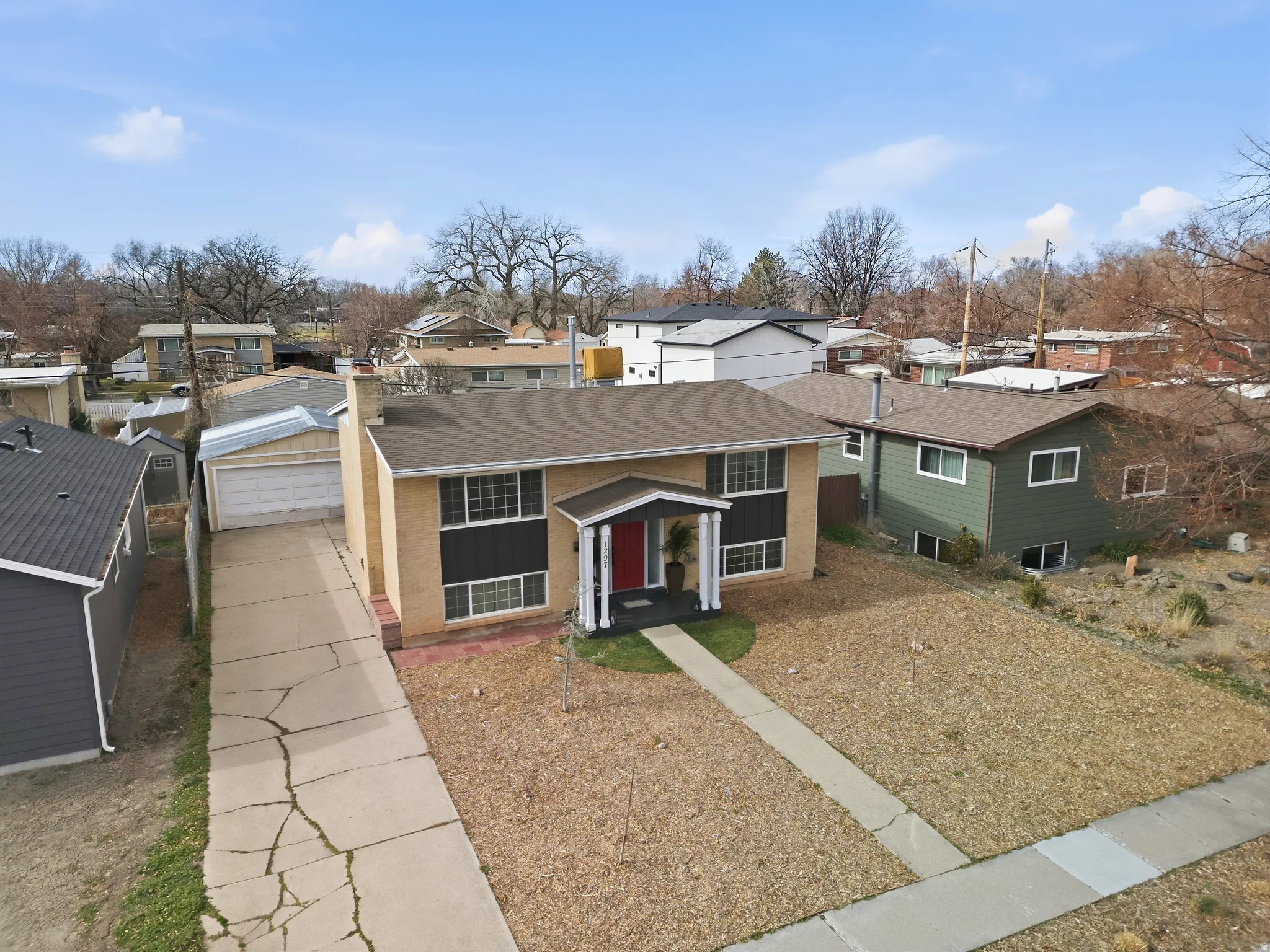 View of front of home featuring a residential view, brick siding, a shingled roof, and driveway