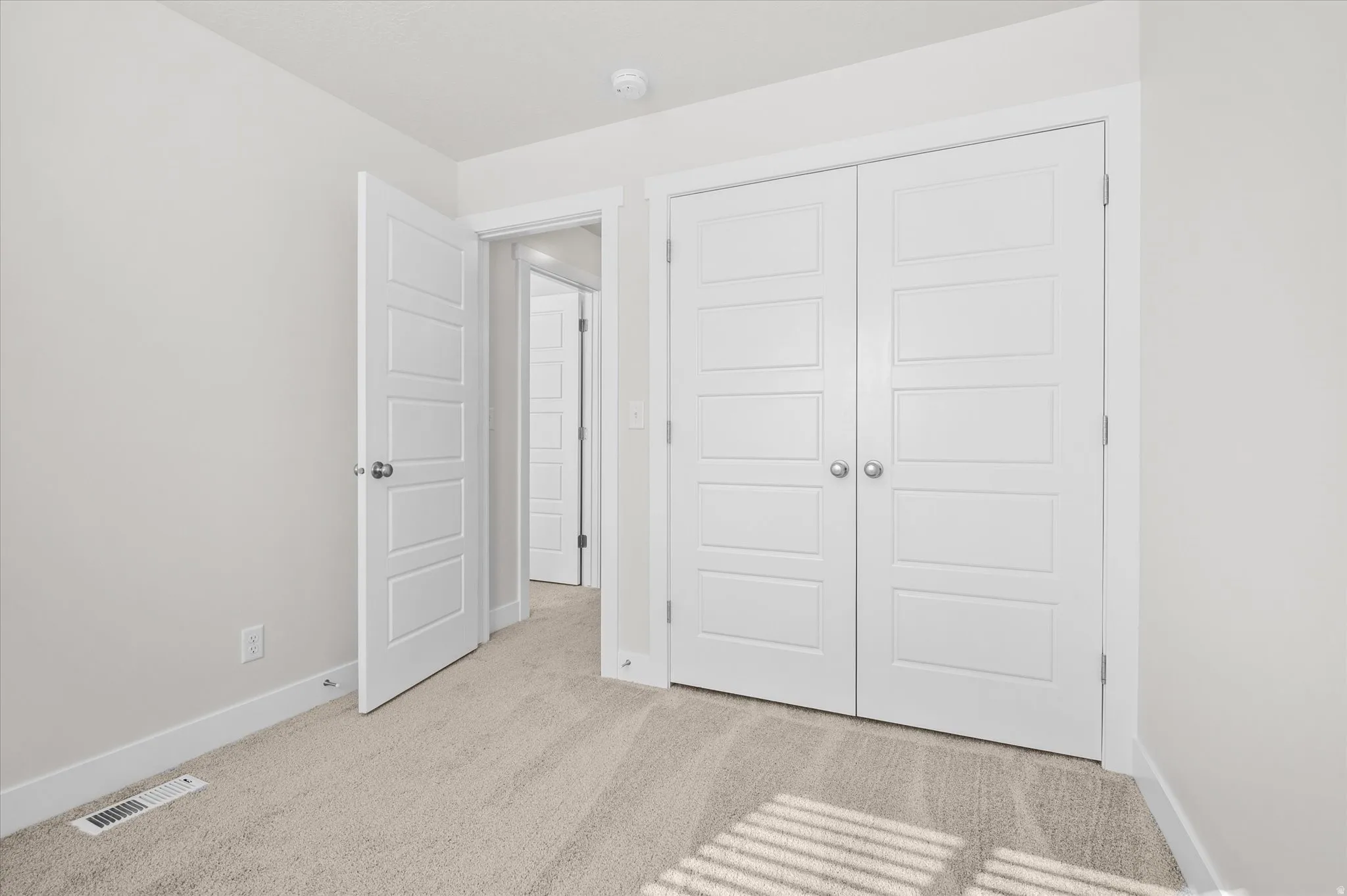 Unfurnished bedroom featuring light carpet and a closet
