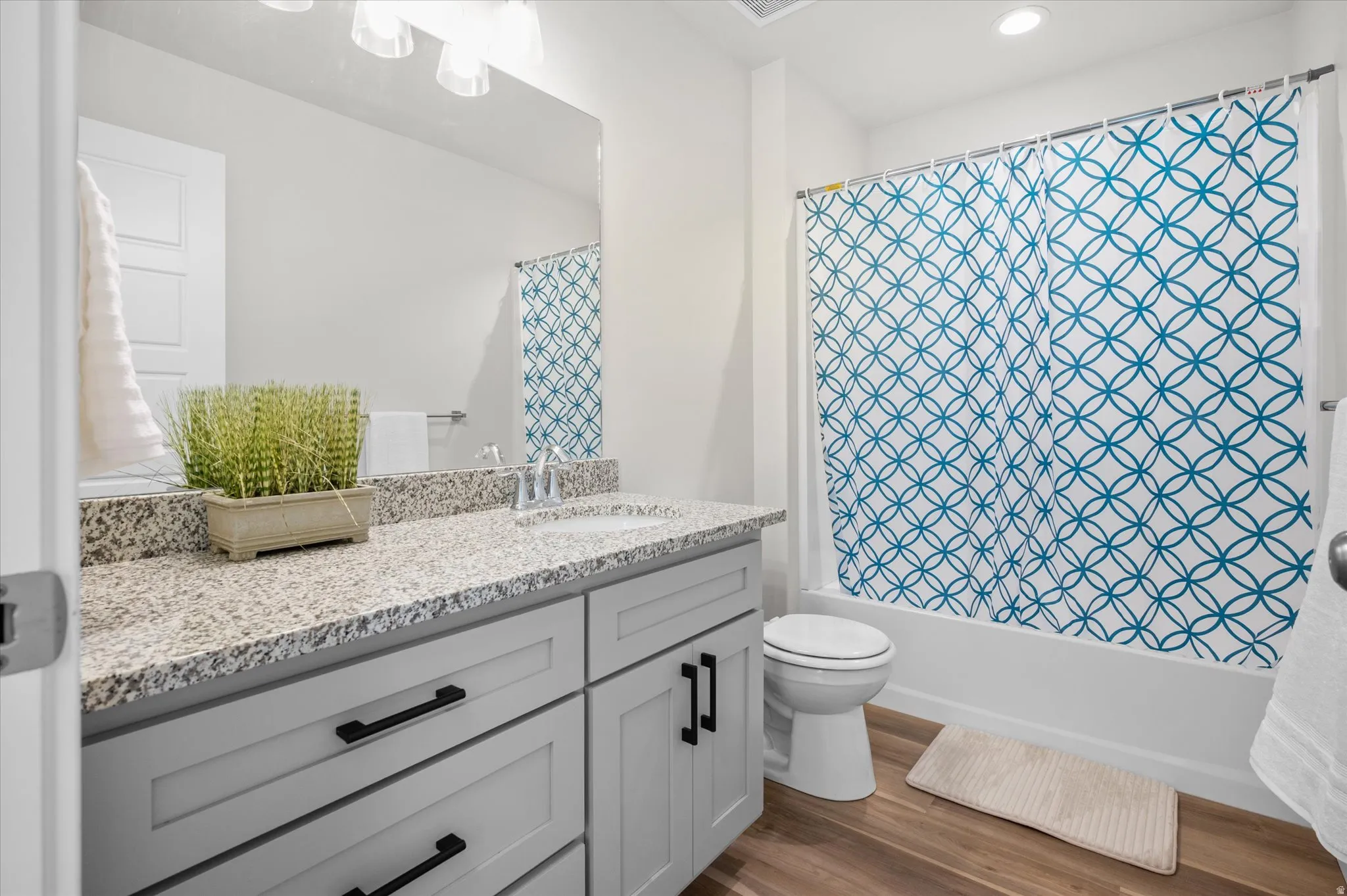 Bathroom with vanity, dark wood-style flooring, shower / bath combination with curtain, and recessed lighting