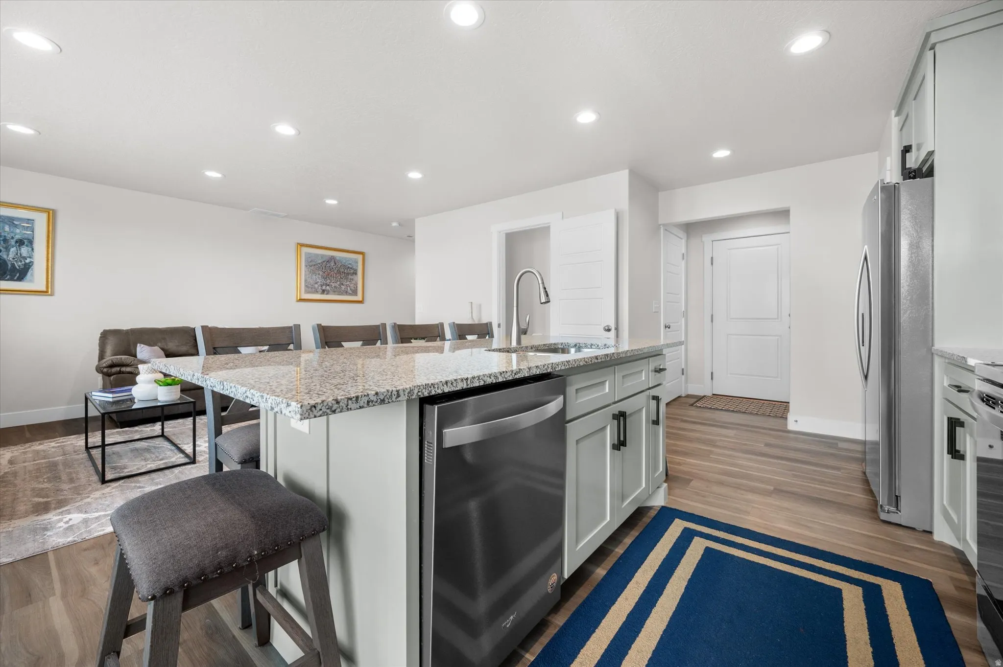 Kitchen with a kitchen breakfast bar, light stone countertops, stainless steel appliances, an island with sink, and recessed lighting