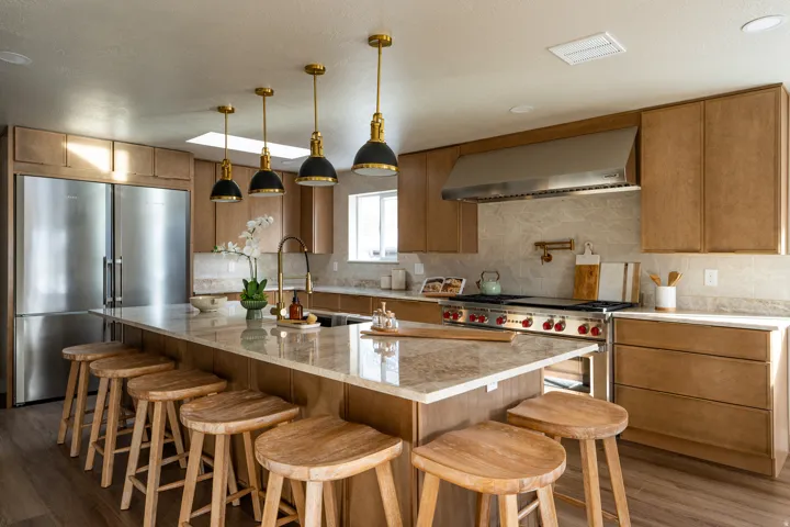 Kitchen with premium appliances, light stone counters, a kitchen breakfast bar, pendant lighting, and dark wood-type flooring