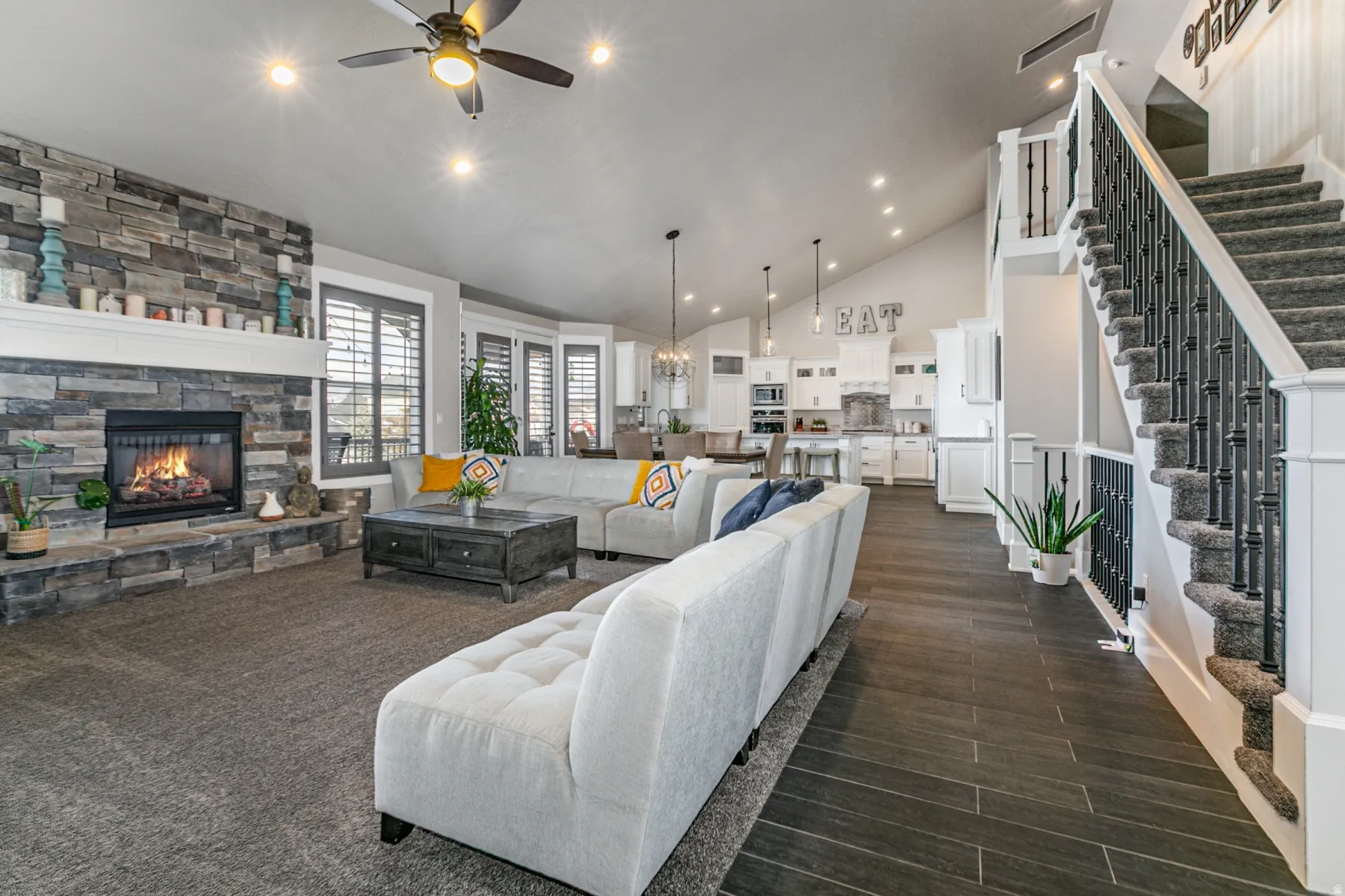 Living room with a fireplace, lofted ceiling, ceiling fan, wood tiled floors, and suspended lighting